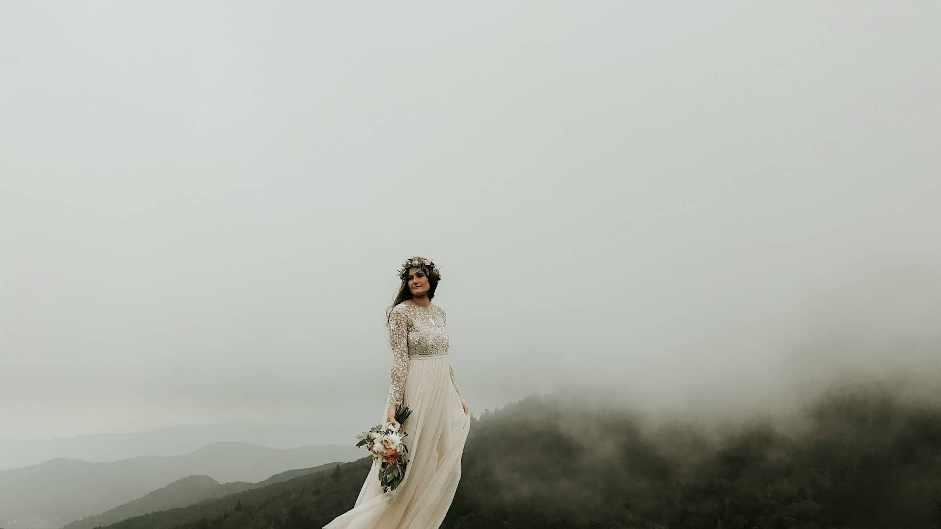 A bride standing on a mountain with misty behind her