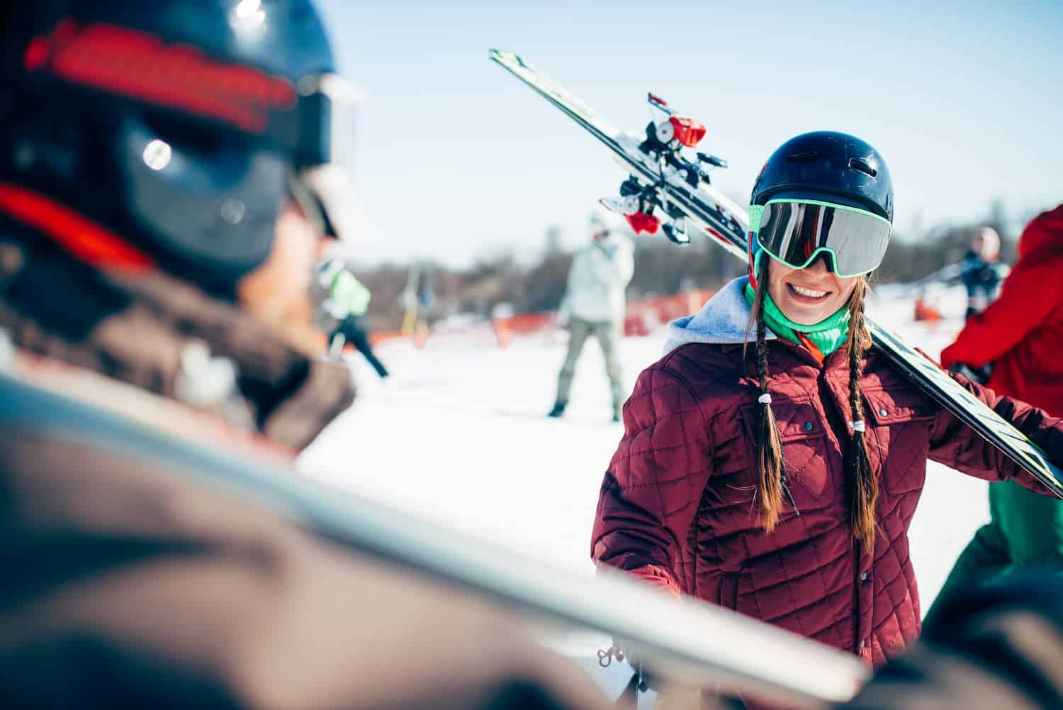 Skiers holding skis over shoulder smiling